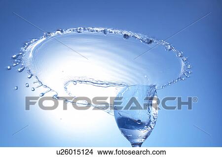 Picture - Water splashing from glass, blue background. Fotosearch