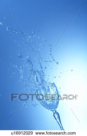 Stock Photo - Water splashing in glass, blue background. Fotosearch