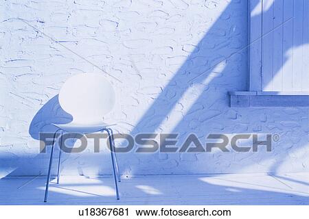 Stock Image - White chair next to white textured wall. Fotosearch