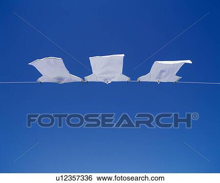 Stock Photograph - White T-shirts hanging on a clothesline under a clear blue sky. Fotosearch