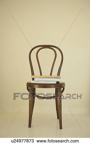 Stock Image - Wooden chair with books stacked on it. Fotosearch