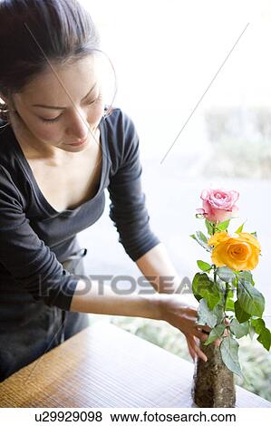 Stock Photo - Young Woman Arranging Flower in Vase. Fotosearch