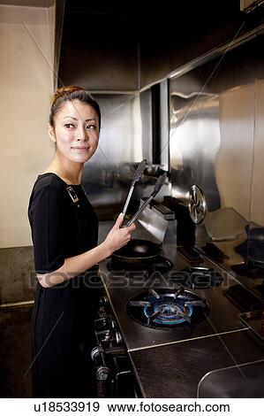 Stock Photo - Young Woman Cooking at Kitchen in Restaurant. Fotosearch