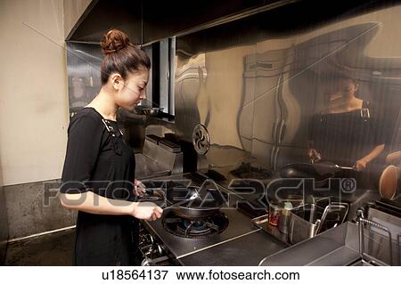 Stock Photo - Young Woman Cooking at Kitchen in Restaurant. Fotosearch