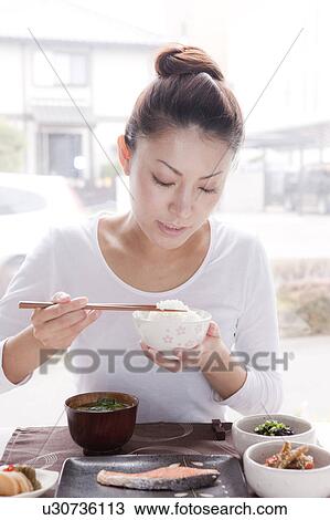 Stock Image - Young Woman Eating Japanese Cuisine. Fotosearch