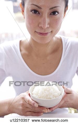 Young Woman Holding Bowl of Rice at Table View Large Photo Image Stock Photo - Young Woman Holding Bowl of Rice at Table. Fotosearch