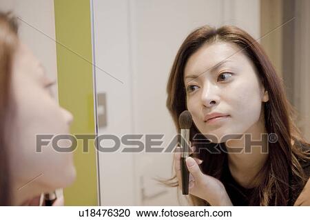 Stock Image - Young Woman Making Up, Looking at Mirror. Fotosearch