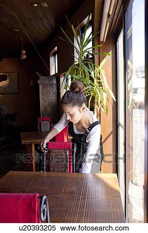 Stock Photography - Young Woman Setting Chair. Fotosearch