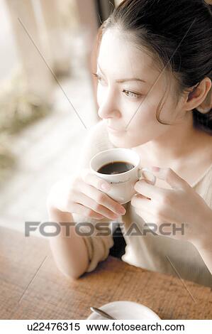 Young Woman Sitting at Table and Holding Coffee Cup View Large Photo Image Stock Photography - Young Woman Sitting at Table and Holding Coffee Cup. Fotosearch