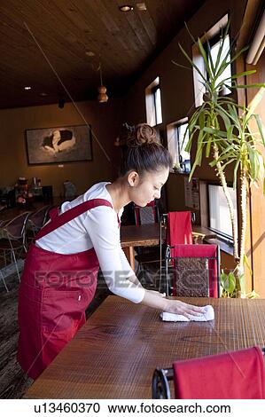 Stock Image - Young Woman Wiping Table. Fotosearch