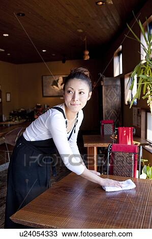 Stock Image - Young Woman Wiping Table. Fotosearch