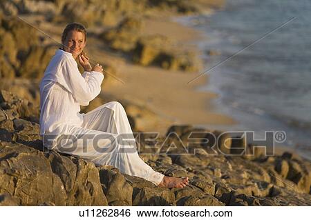 Stock Photograph - Woman on rocky shoreline. Fotosearch
