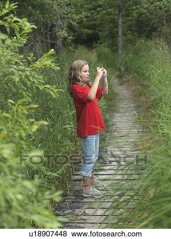 Stock Photo - Young girl on pathway taking a picture, Lake of the Woods, Ontario, Canada. Fotosearch