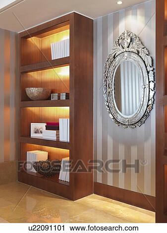 Stock Image - Bookcase and striped wallpaper in modern home. Fotosearch