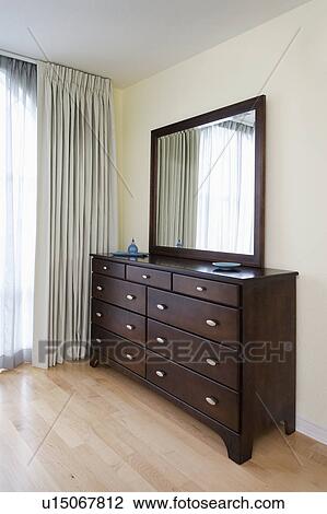 Stock Image - Contemporary wooden dresser on hardwood floor. Fotosearch