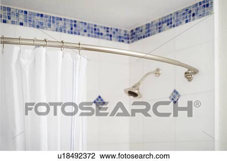 Stock Image - Detail shower curtain and shower head in blue and white tiled shower. Fotosearch