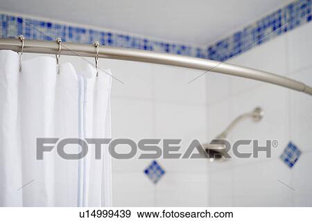 Stock Photo - Detail shower curtain and shower head in blue and white tiled shower. Fotosearch