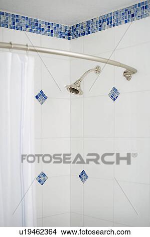 Picture - Detail shower curtain and showerhead in blue and white tiled shower. Fotosearch