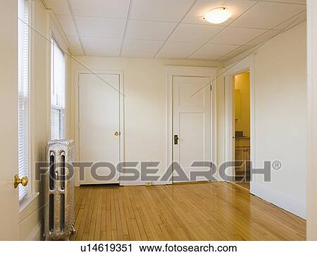 Stock Image - Empty room in apartment with hardwood floor and heater. Fotosearch