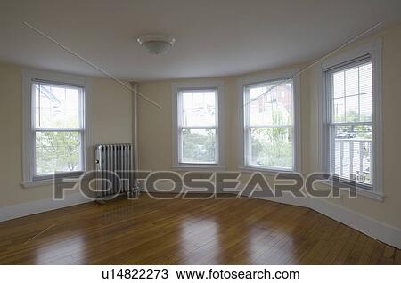 Stock Image - Empty room in apartment with hardwood floor and heater. Fotosearch