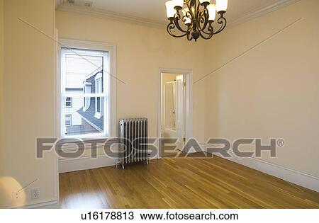 Stock Image - Empty room in apartment with hardwood floor and heater. Fotosearch