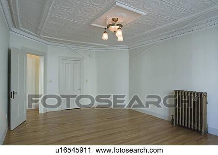 Stock Image - Empty room in apartment with hardwood floor and heater. Fotosearch
