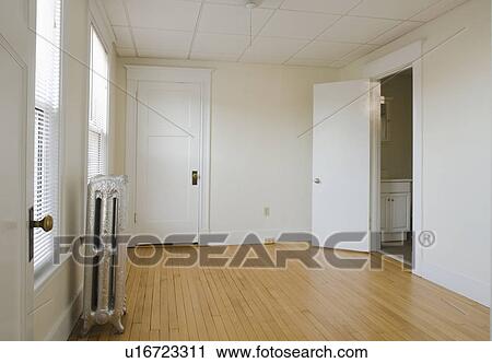 Stock Image - Empty room in apartment with hardwood floor and heater. Fotosearch