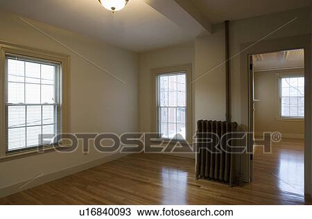 Stock Image - Empty room in apartment with hardwood floor and heater. Fotosearch
