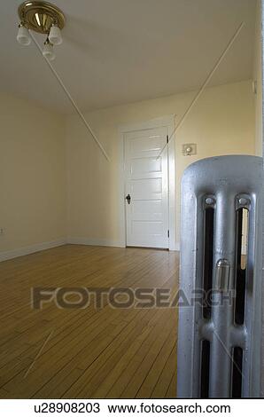 Stock Image - Empty room in apartment with hardwood floor and heater. Fotosearch