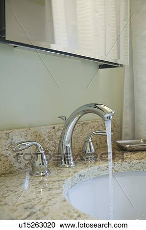 Stock Image - Faucet running in bathroom sink. Fotosearch