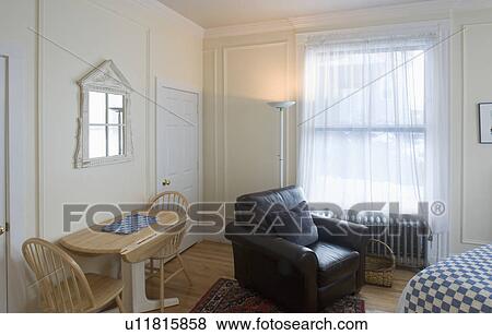 Stock Photo - Kitchen table and armchair in small studio apartment. Fotosearch