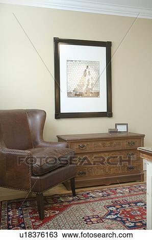 Stock Image - Leather wing backed chair and dresser. Fotosearch