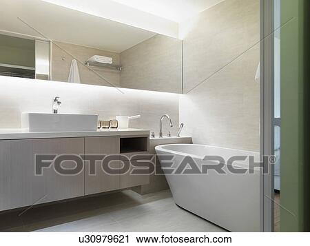 Stock Image - Light colored modern bathroom with large bathtub. Fotosearch