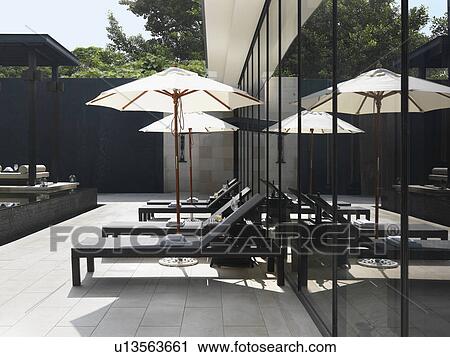 Lounge chairs and umbrellas by pool View Large Photo Image Stock Image - Lounge chairs and umbrellas by pool. Fotosearch