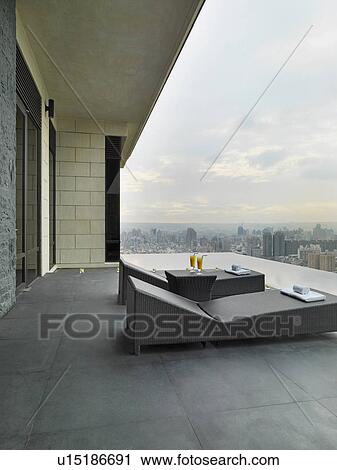 Stock Image - Lounge chairs on patio overlooking city. Fotosearch