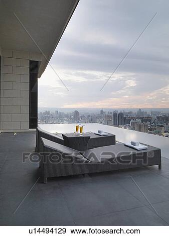 Stock Photo - Lounge chairs on patio overlooking city. Fotosearch