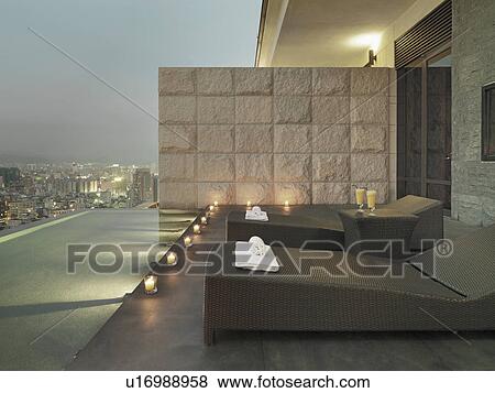 Stock Photo - Lounge chairs on patio overlooking city. Fotosearch