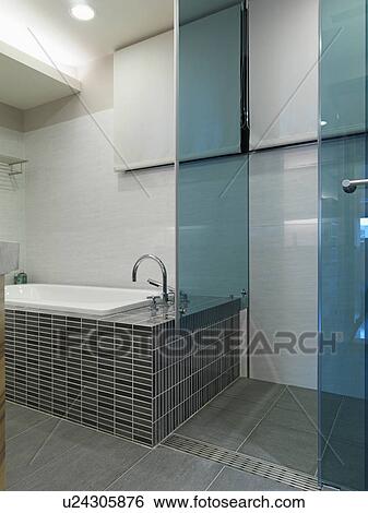 Stock Photograph - Mosaic tile bathtub and glass shower. Fotosearch
