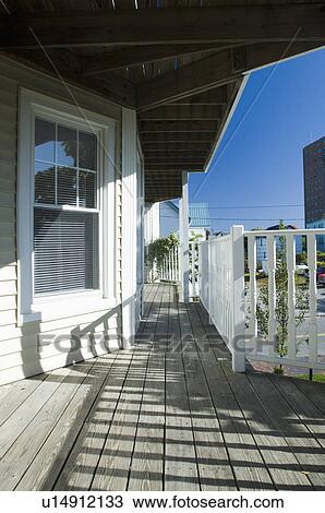 Stock Image - Railing shadows on wooden front porch. Fotosearch