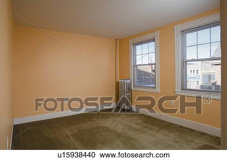 Stock Image - Room in empty apartment with carpet and a heater. Fotosearch