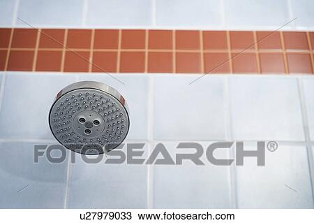 Stock Image - Showerhead in blue and orange tiled shower. Fotosearch