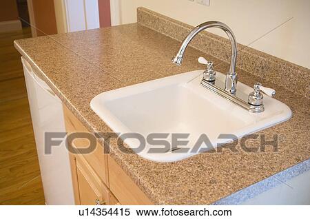 Stock Photography - Small kitchen sink and mini fridge in apartment. Fotosearch