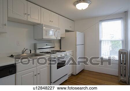 Stock Photo - White stove and kitchen in empty apartment. Fotosearch