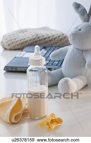 Stock Photo - Baby bottle beside laptop. Fotosearch