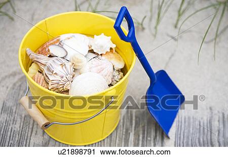 Stock Image - Beach shovel and pail of shells. Fotosearch