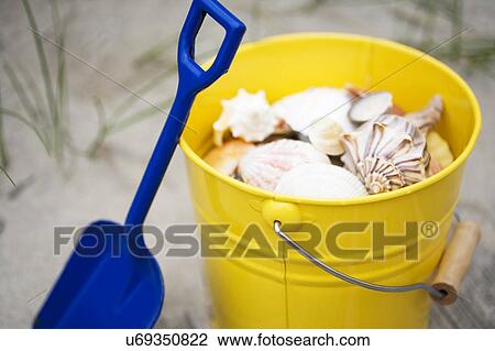 Stock Image - Beach shovel and pail of shells. Fotosearch