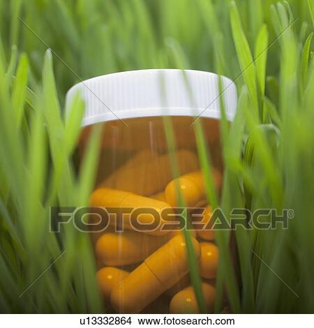Picture - Bottle of pills in grass. Fotosearch