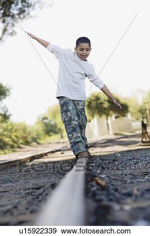 Stock Photo - Boy walking on railroad track. Fotosearch