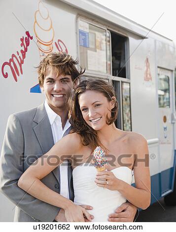 Stock Image - Bride and groom eating ice cream. Fotosearch