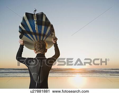 Stock Image - Child holding surfboard. Fotosearch